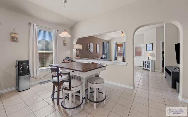 dining room featuring a ceiling fan, arched walkways, light tile patterned flooring, and vaulted ceiling