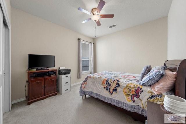 bedroom with light carpet, ceiling fan, visible vents, and baseboards