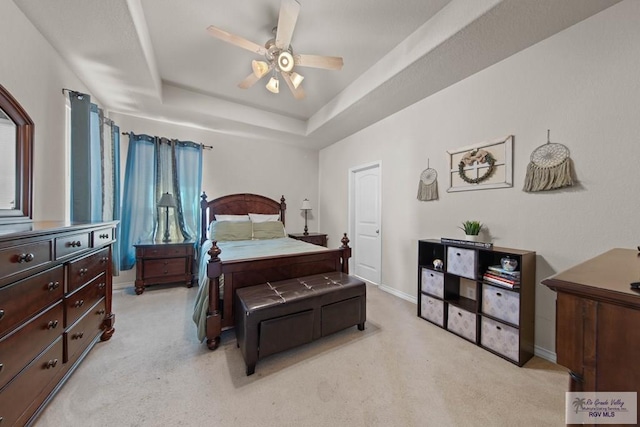 bedroom featuring baseboards, a tray ceiling, and light colored carpet