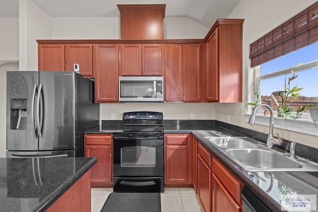 kitchen with light tile patterned floors, stainless steel appliances, vaulted ceiling, a sink, and dark stone counters