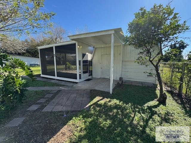 rear view of house with a yard and a sunroom