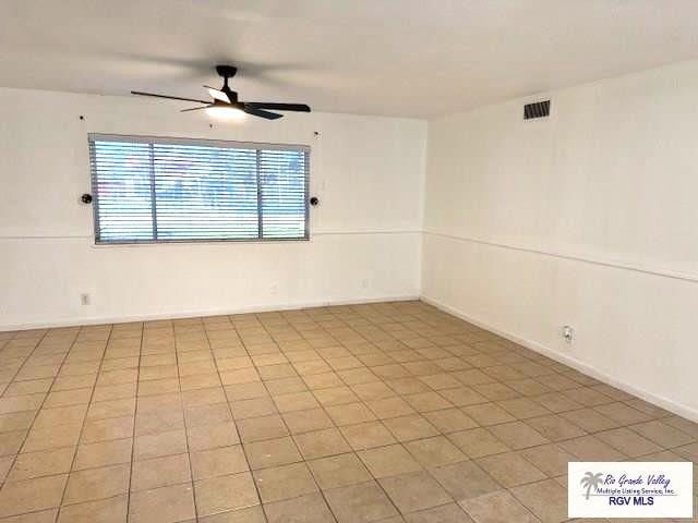 tiled spare room with ceiling fan