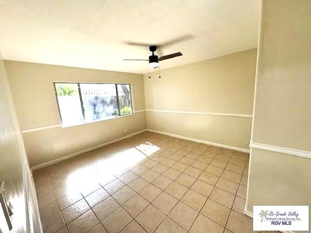 tiled spare room featuring ceiling fan