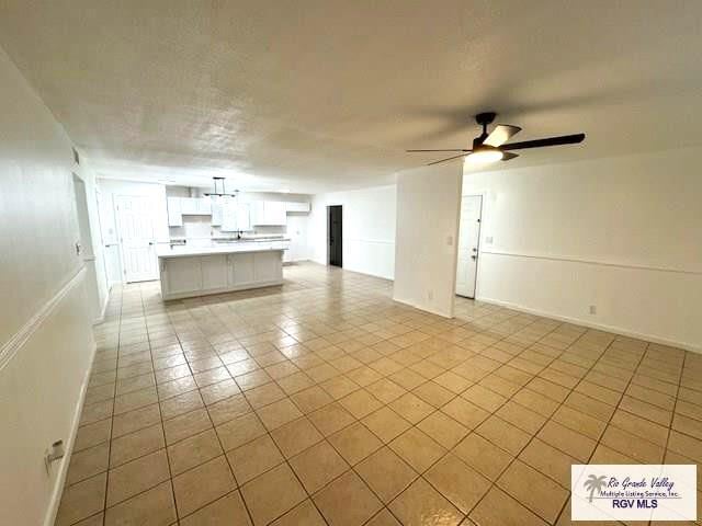 unfurnished living room with ceiling fan and light tile patterned floors