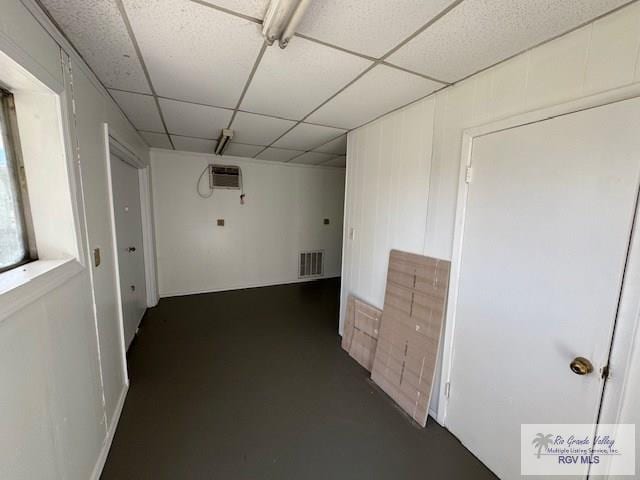 hallway with a drop ceiling and a wall mounted air conditioner