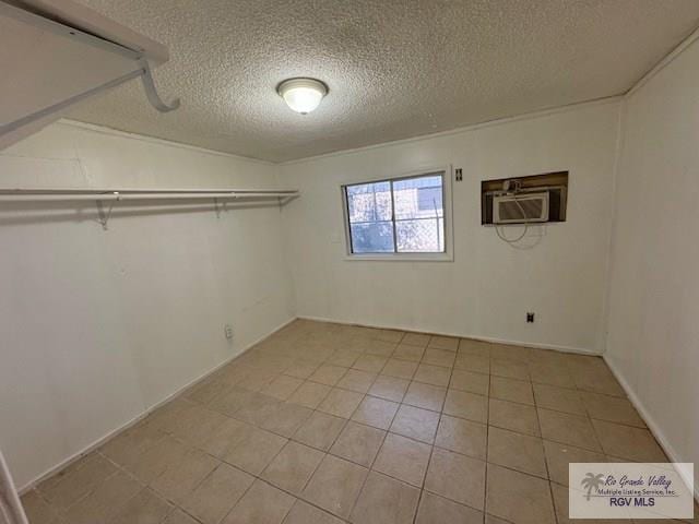 basement with light tile patterned floors, a textured ceiling, and an AC wall unit