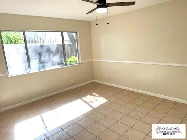 spare room with ceiling fan, plenty of natural light, and light tile patterned floors