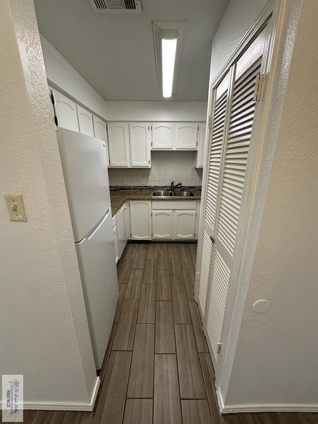 kitchen featuring dark hardwood / wood-style flooring, backsplash, sink, white cabinets, and white fridge