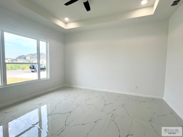 unfurnished room with a raised ceiling and ceiling fan