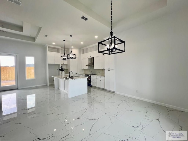 kitchen featuring hanging light fixtures, a center island with sink, white cabinets, a chandelier, and range with electric stovetop