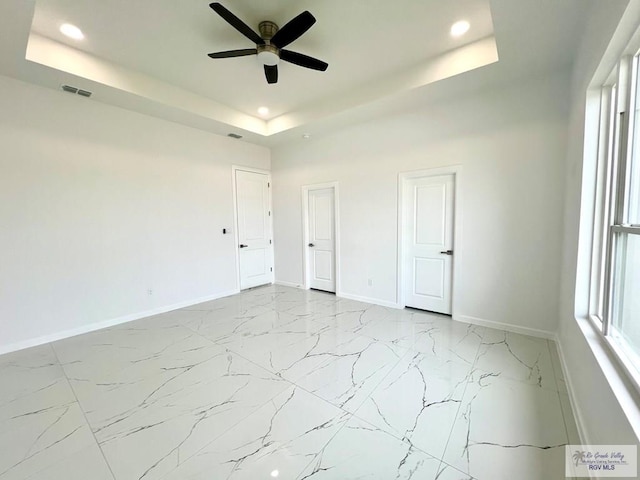 interior space with ceiling fan and a tray ceiling