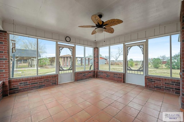 unfurnished sunroom featuring ceiling fan and a wealth of natural light