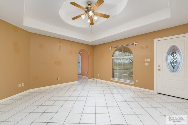 entryway with a raised ceiling, ceiling fan, and light tile patterned flooring