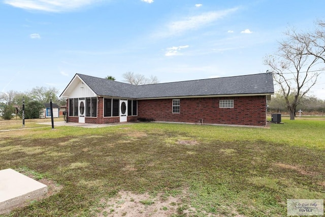 exterior space featuring central AC unit, a lawn, and a sunroom