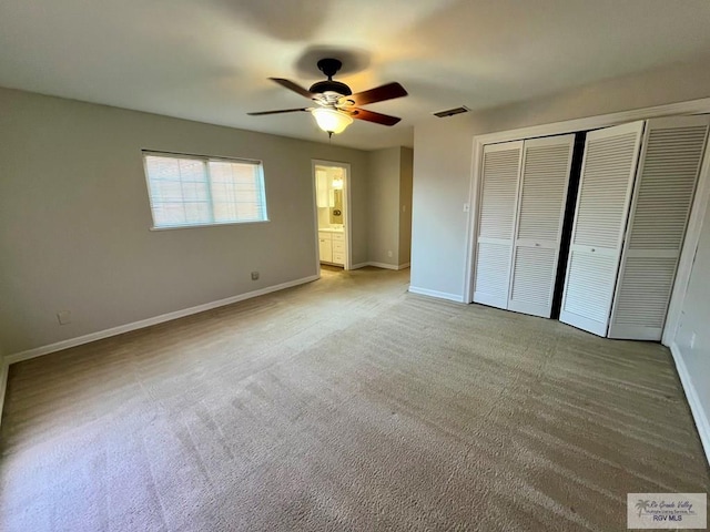 unfurnished bedroom with light carpet, ensuite bathroom, and ceiling fan