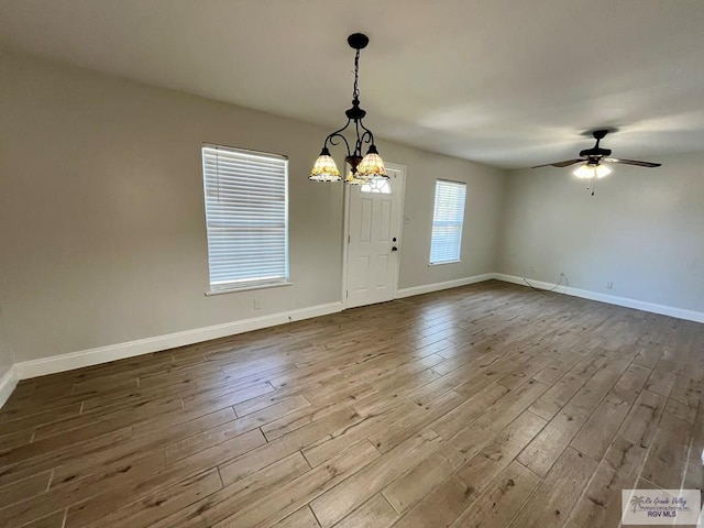 empty room featuring hardwood / wood-style floors and ceiling fan with notable chandelier