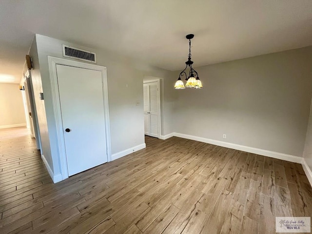 unfurnished dining area featuring a notable chandelier and light hardwood / wood-style flooring