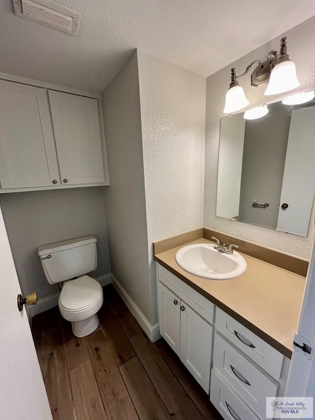 bathroom with toilet, vanity, and hardwood / wood-style flooring