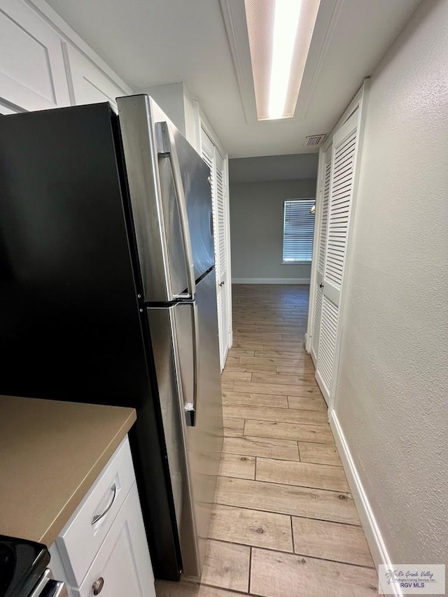 kitchen featuring white cabinets, stainless steel fridge, and light hardwood / wood-style flooring