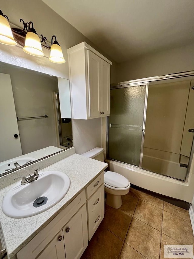 full bathroom featuring tile patterned floors, vanity, toilet, and bath / shower combo with glass door