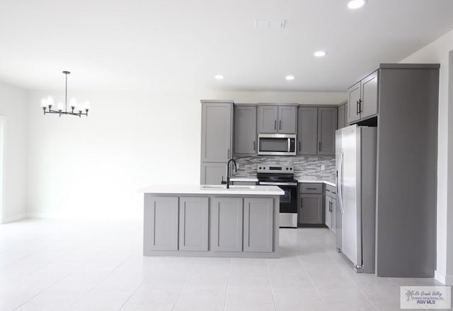 kitchen with gray cabinetry, a kitchen island with sink, sink, and appliances with stainless steel finishes