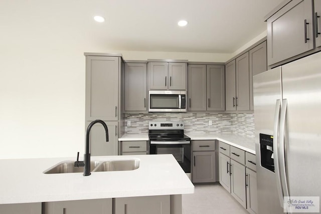 kitchen featuring gray cabinetry, backsplash, sink, and stainless steel appliances