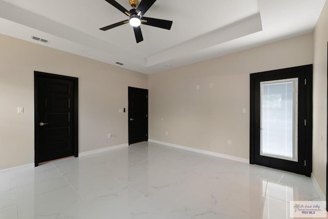 spare room with ceiling fan and a tray ceiling