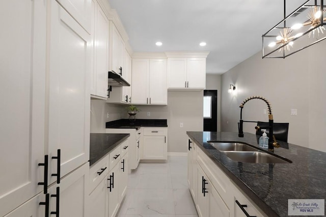 kitchen featuring sink, white cabinetry, decorative light fixtures, and dark stone countertops