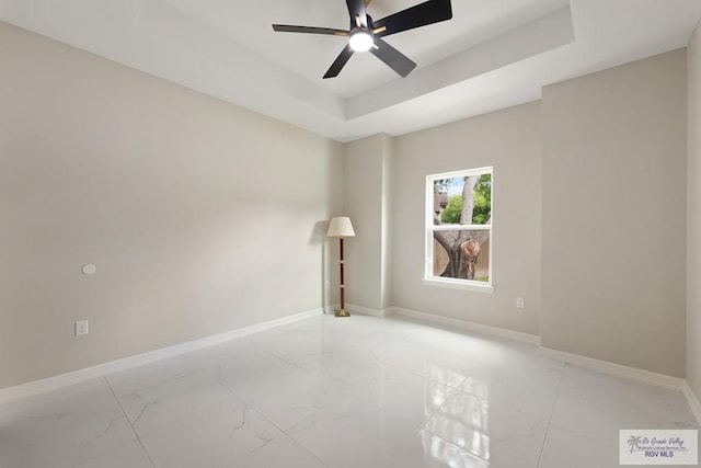 unfurnished room with ceiling fan and a tray ceiling