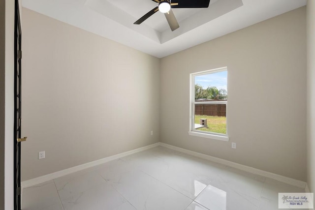 unfurnished room featuring a raised ceiling and ceiling fan