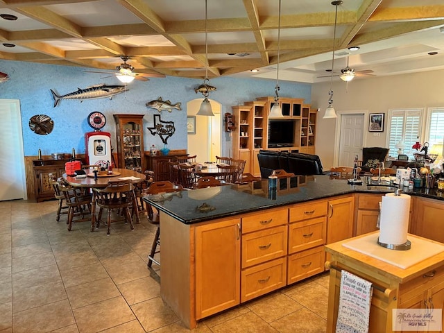 kitchen with beam ceiling, coffered ceiling, decorative light fixtures, a breakfast bar, and light tile patterned floors