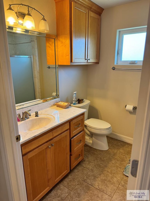 bathroom featuring tile patterned flooring, vanity, toilet, and a shower with door