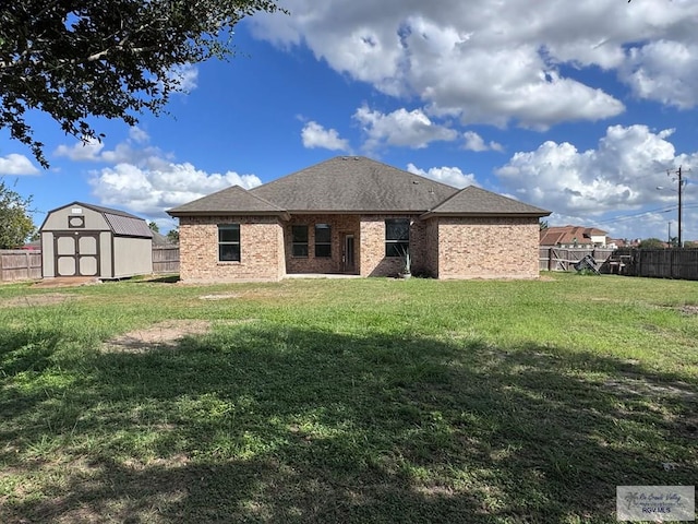 rear view of property with a yard and a storage unit