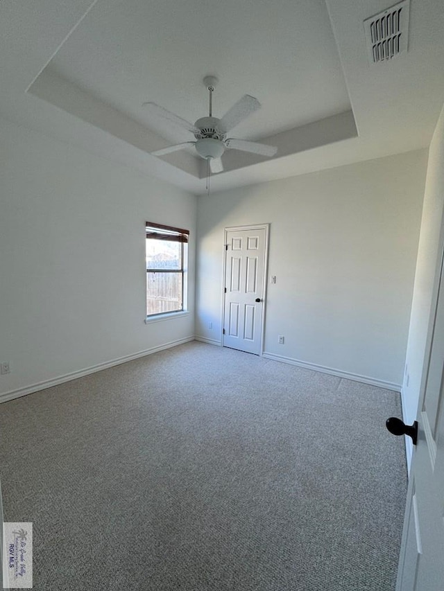 carpeted spare room featuring ceiling fan and a tray ceiling