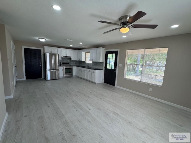 kitchen with stainless steel appliances, baseboards, dark countertops, under cabinet range hood, and recessed lighting