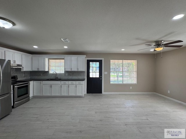 kitchen featuring appliances with stainless steel finishes, baseboards, a sink, dark countertops, and recessed lighting