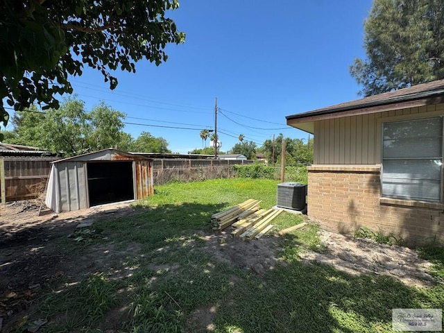 view of yard featuring a shed, central air condition unit, and an outbuilding