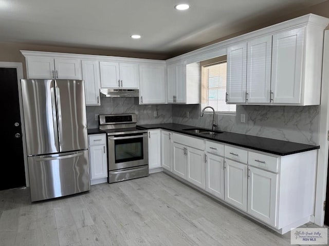kitchen with appliances with stainless steel finishes, a sink, under cabinet range hood, white cabinets, and recessed lighting