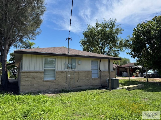 view of side of home featuring brick siding, cooling unit, and a yard