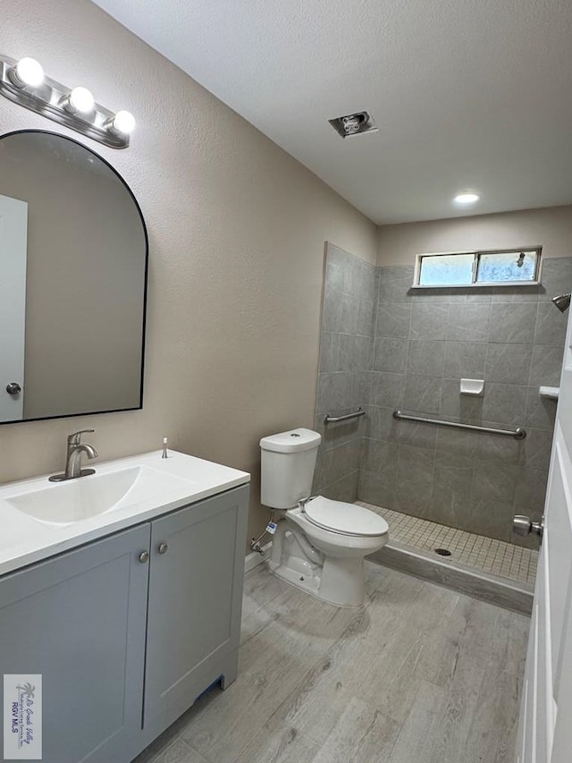 full bath featuring wood finished floors, toilet, a walk in shower, and vanity