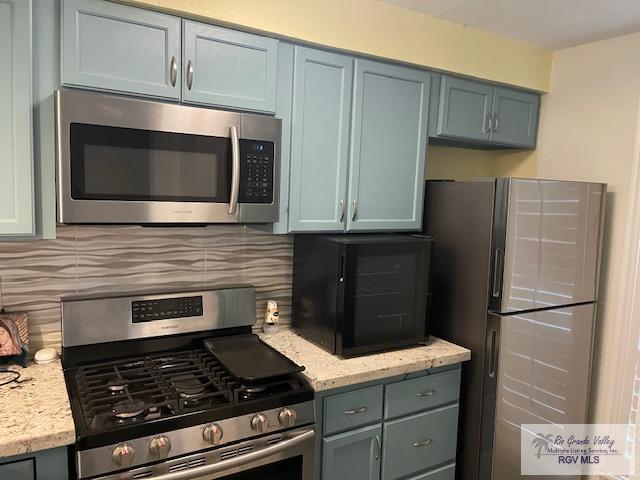 kitchen with decorative backsplash, light stone countertops, and stainless steel appliances