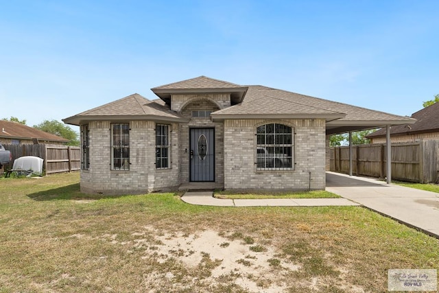 9315 Los Olmos Dr, Los Fresnos, TX 78566 - french country inspired facade with an attached carport, brick siding, concrete driveway, and roof with shingles