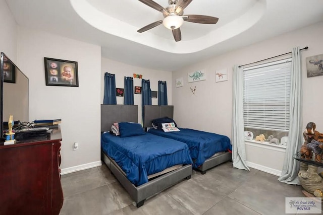 bedroom featuring ceiling fan, concrete floors, and a tray ceiling