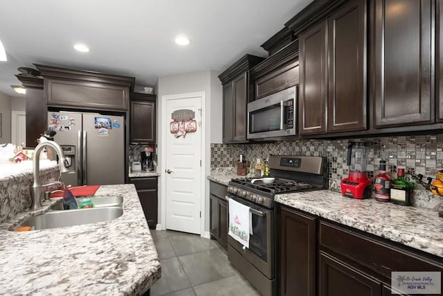 kitchen featuring appliances with stainless steel finishes, tasteful backsplash, dark brown cabinetry, sink, and light tile patterned floors