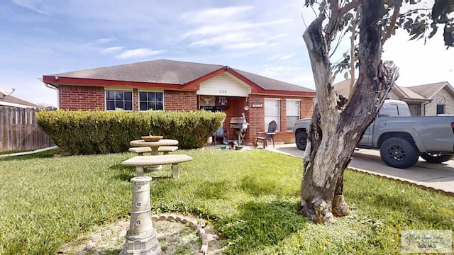 view of front of home with brick siding, a front lawn, and fence