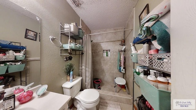 bathroom featuring tiled shower, a textured wall, a textured ceiling, and toilet