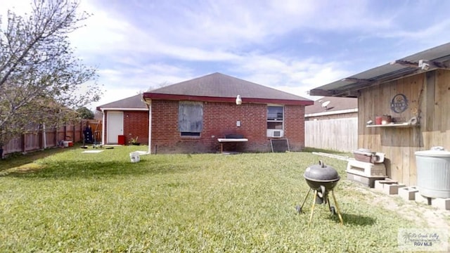 back of property with a yard, brick siding, and a fenced backyard