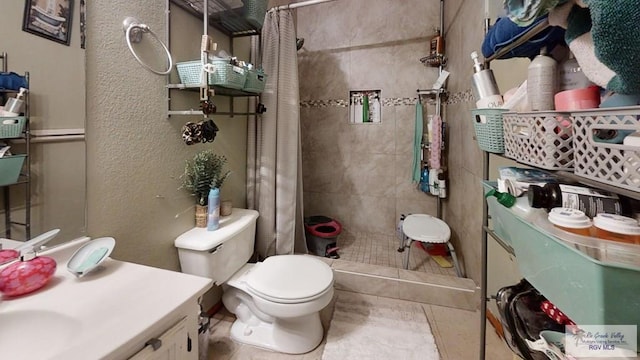 full bath featuring a stall shower, a textured wall, vanity, and toilet