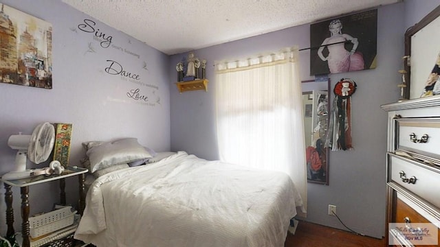 bedroom with multiple windows, dark wood finished floors, and a textured ceiling