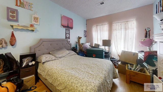 bedroom featuring a textured ceiling, wood finished floors, and visible vents